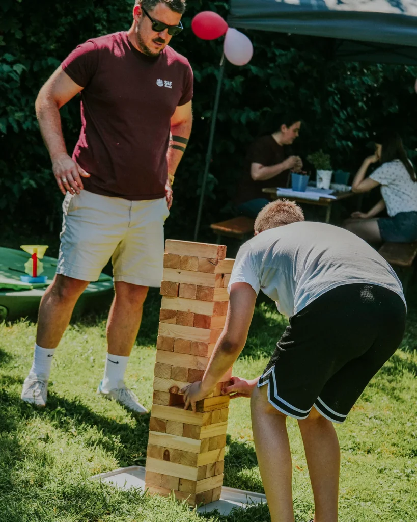 Ein Mann spielt mit einem Jungen Jenga mit XXL Klötzen
